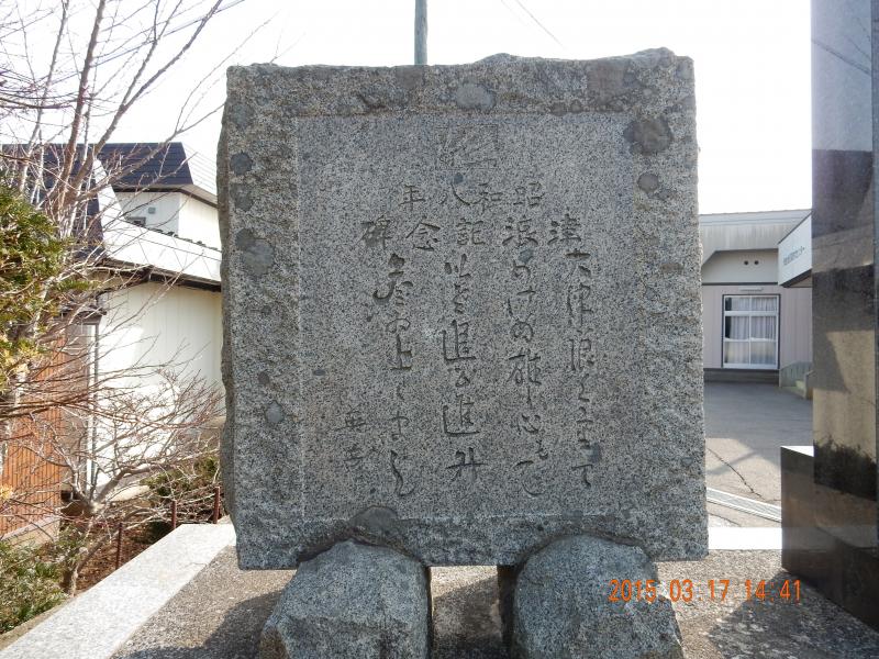 建物の横に立てられた、文字が刻まれた四角い石碑の写真