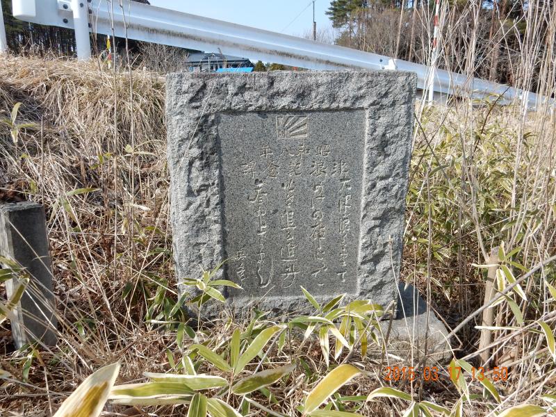 茶色の草木が生える中に立てられた四角い石碑の写真