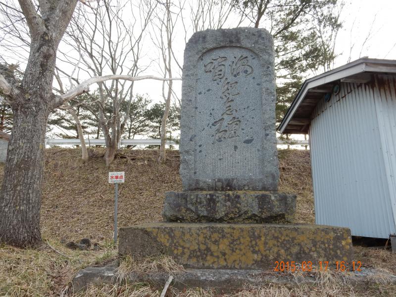 三段重ねの土台の上に立つ、角が丸く縦に長い長方形の石碑の写真