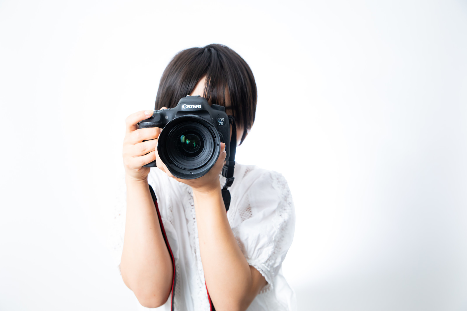 白い服を着た人がカメラを構えている写真
